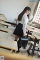 A woman standing in a classroom holding a briefcase.