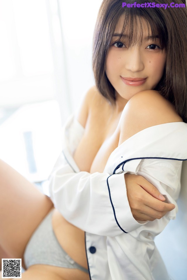 A woman in a white shirt and gray panties posing for a picture.