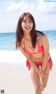 A woman in a pink bikini standing on a beach.