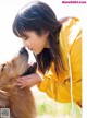 A woman in a yellow jacket is kissing a dog.