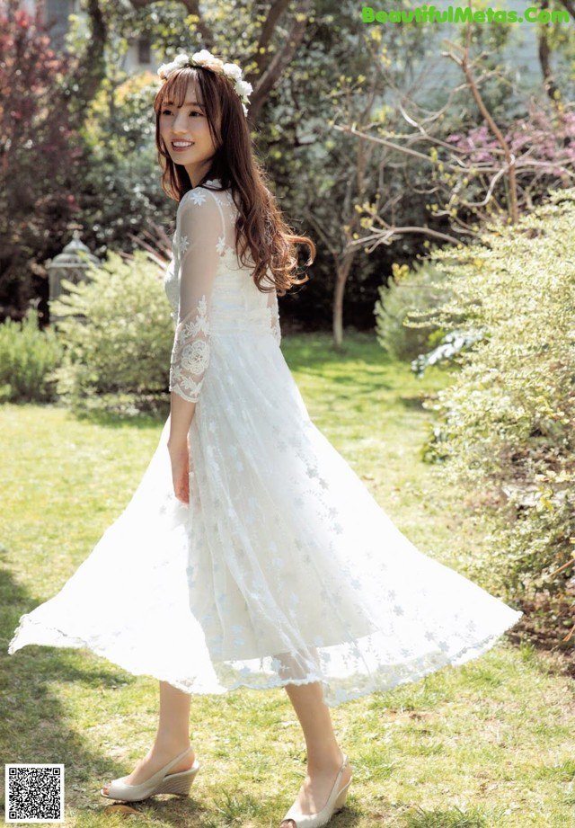 A woman in a white dress standing in the grass.