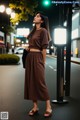 A woman standing on the side of a street at night.