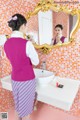 A woman standing in front of a mirror in a bathroom.