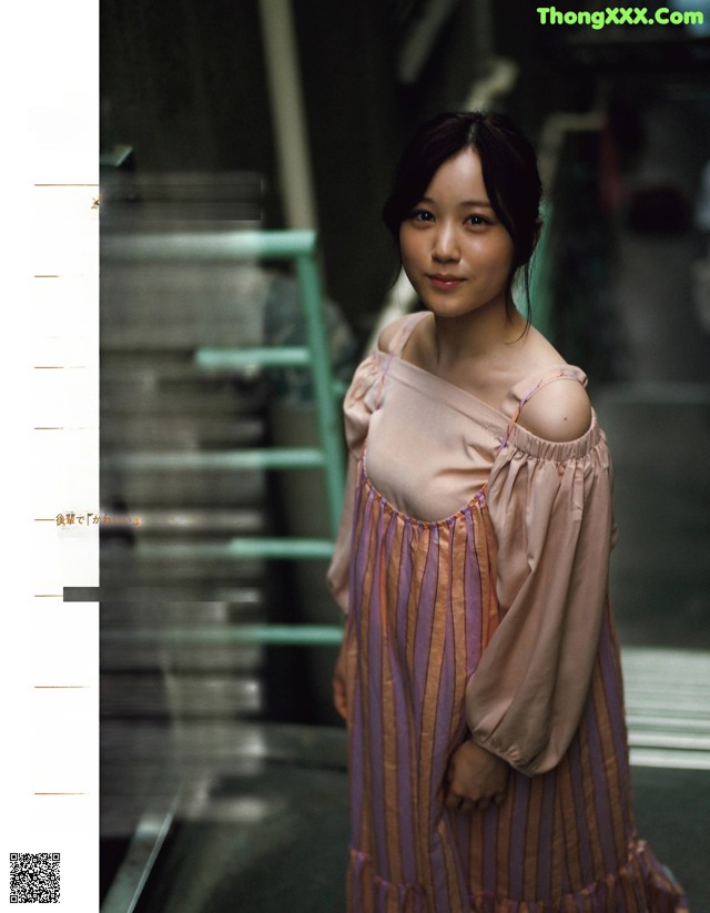 A woman in a pink dress standing in front of a window.