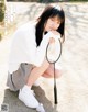 A young woman crouching down with a badminton racket.