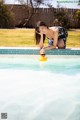 A woman in a bathing suit playing with a rubber duck in a pool.