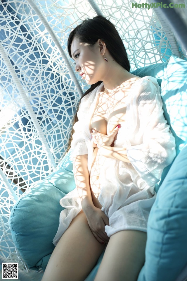 A woman in a white dress sitting on a blue chair.
