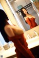 A woman in a red dress standing in front of a mirror.