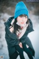 A woman wearing a blue hat sitting in the snow.