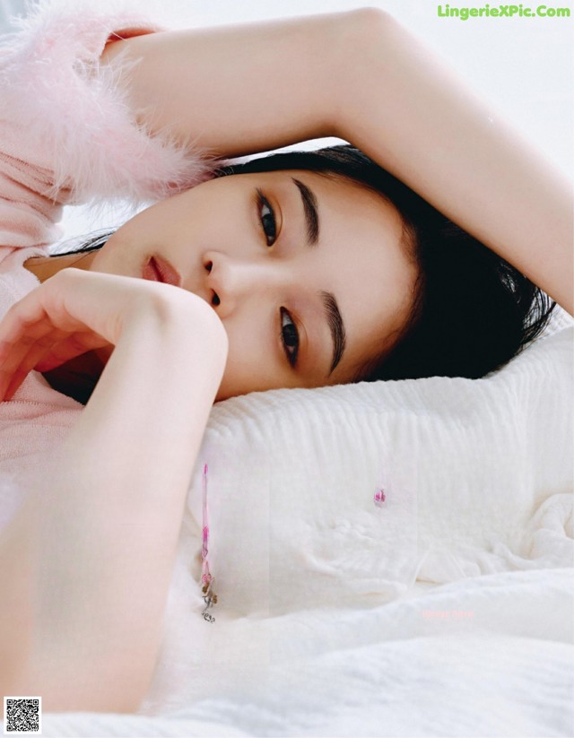 A woman laying on top of a bed in a magazine.