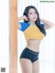 A woman in a yellow and blue shirt and black panties.