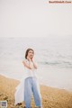 A woman standing on a beach next to the ocean.