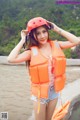 A woman wearing an orange life jacket and a red helmet.