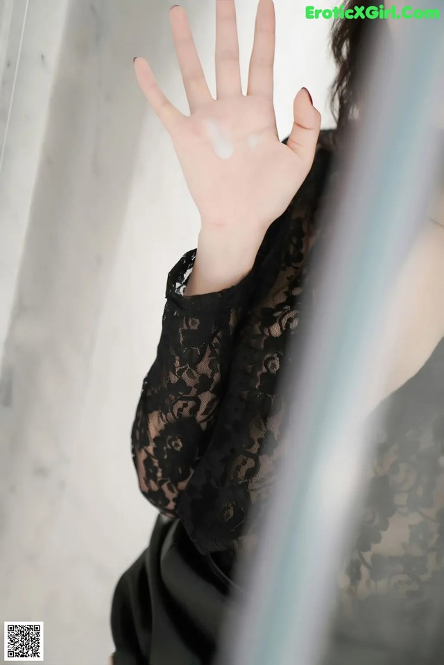 A woman in a black dress holding her hand up to the camera.