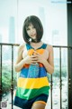 A woman in a colorful tank top posing on a balcony.